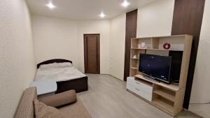 ein kleines Wohnzimmer mit einem Bett und einem TV in der Unterkunft Уютные апартаменты 1 комн квартира, ЖК Губернский in Krasnodar