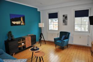 ein Wohnzimmer mit einer blauen Wand und einem blauen Stuhl in der Unterkunft Apartmenthaus am Zimmerplatz in Hofheim am Taunus