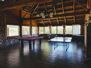 2 mesas de ping pong en una habitación con ventanas en Apart & Cabañas "Cañada del Sauce" en Nono