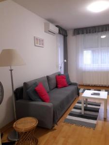 a living room with a gray couch and red pillows at Max Thermal Apartman in Hévíz