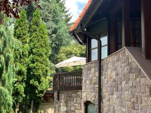 a house with a stone wall and an umbrella at Tulipán Vendégház in Miskolc