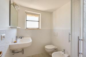 bagno bianco con lavandino e servizi igienici di Oltremare Appartamenti a Principina a Mare