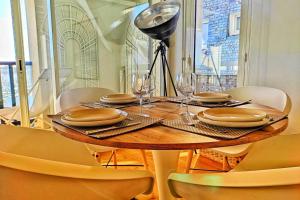 a wooden table with plates and wine glasses on it at Les Balcons de La Trinité - Vue sur mer et le port in La Trinité-sur-Mer