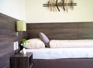 Schlafzimmer mit einem weißen Bett mit einem Kopfteil aus Holz in der Unterkunft eee Hotel Gunskirchen in Gunskirchen