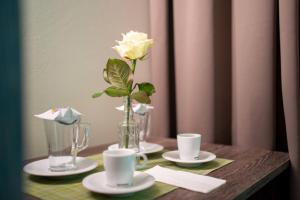 uma mesa com duas chávenas e um vaso com uma rosa amarela em eee Hotel Gunskirchen em Gunskirchen