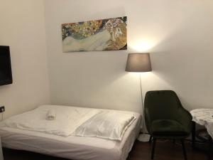 ブダペストにあるCorso Apartmentのベッドルーム1室(ベッド1台、椅子、絵画付)