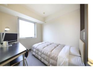 1 dormitorio con cama, escritorio y ventana en R&B Hotel Tokyo Toyocho - Vacation STAY 14234v, en Tokio