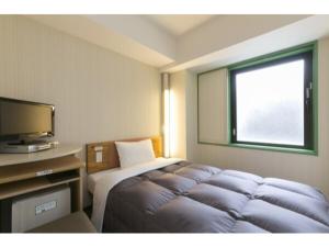 横浜市にあるR&B Hotel Shin Yokohama Ekimae - Vacation STAY 14693vのベッドとテレビが備わるホテルルームです。