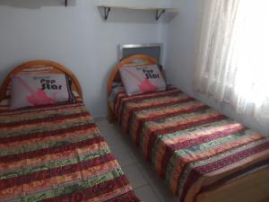 two beds in a small room with a bedspread at Aparkit Vila Caiçara in Solemar