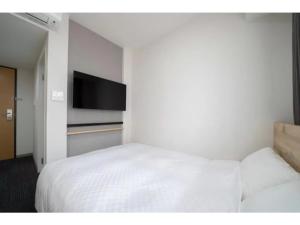 a bedroom with a white bed and a flat screen tv at R&B Hotel Nagoya Shinkansenguchi - Vacation STAY 15002v in Nagoya