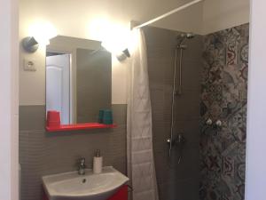 a bathroom with a sink and a shower with a mirror at Szélrózsa apartmanház in Velence