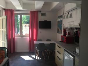 a kitchen with red curtains and a table and chairs at Szélrózsa apartmanház in Velence