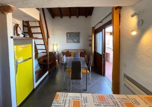 ein Wohnzimmer mit einem Tisch und einem gelben Kühlschrank in der Unterkunft SAN TEODORO PUNTA EST AMPIO TRILOCALE VISTA MARe in Capo Coda Cavallo