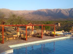 a swimming pool with tables and chairs next to the water at Apart & Cabañas "Cañada del Sauce" in Nono