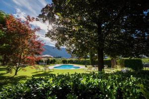 una piscina en un patio con sillas y un árbol en Pension Sandhofer en Nalles