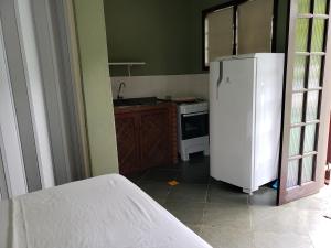 a kitchen with a white refrigerator and a stove at Chales Terra Pura in Camburi
