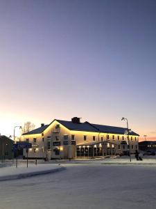 un grand bâtiment dans un parking au coucher du soleil dans l'établissement Hotel Lapland River, à Pajala