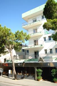 a tall white building with trees in front of it at Acapulco Beach in Lido di Jesolo