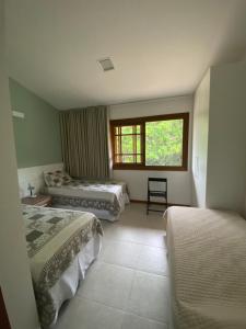 ein Hotelzimmer mit zwei Betten und einem Fenster in der Unterkunft Apartamento 2 suítes em condomínio de luxo no centro in Praia do Forte + 34 Fotos
