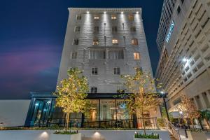 un edificio alto y blanco con árboles delante en One11 Hotel en Nueva Orleans