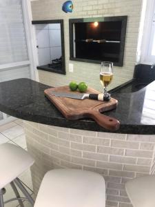 a counter with a glass of wine and a cutting board at Casa incrível a Beira Mar! 3 qtos Ponta do Papagaio in Palhoça