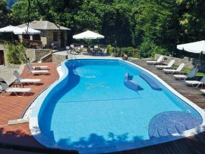 a large blue swimming pool with chairs and umbrellas at Amalthia Traditional Guesthouse in Tsagarada