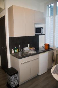eine weiße Küche mit einer Spüle und einer Mikrowelle in der Unterkunft Appartement palais plages in Cannes
