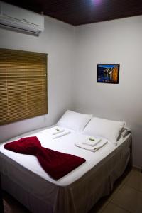 a bedroom with a white bed with a red blanket on it at Pousada Raizes in Sao Jorge