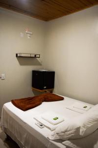a bedroom with a bed with white sheets and a television at Pousada Raizes in Sao Jorge