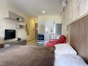格齊拉的住宿－Cast Apartments，一间卧室配有一张床和一张红色椅子,还设有一间厨房