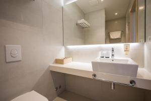 a bathroom with a sink, tub, toilet and mirror at Hotel Osmine in Slano