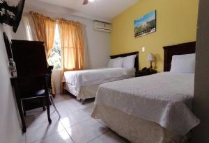 een hotelkamer met 2 bedden en een raam bij Hotel San Jose Hostal in San Salvador