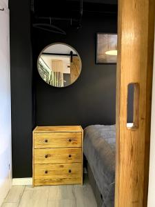 a bedroom with a wooden dresser and a mirror at Apartament1 Tri-City Oliwa Ogród, prywatne wejście in Gdańsk