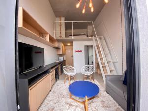 Habitación pequeña con mesa, sillas y escalera. en 45LOFT EM DE MARILIA TODO DECORADO/ARCOND, en Marília