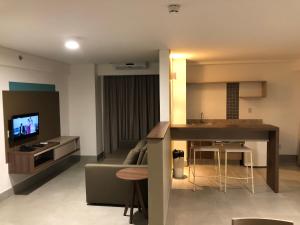 un soggiorno con divano e una cucina con TV di Apto Master em Olímpia Park Resort a Olímpia