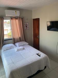 um quarto com uma grande cama branca e uma janela em Pôr do sol apartamentos em Fortaleza