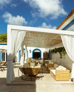 a patio with couches and chairs under a pergola at Hotel Solar do Arco in Cabo Frio