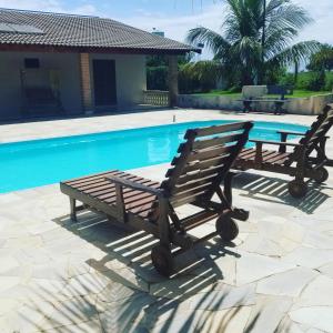 a bench and a table next to a swimming pool at Recanto Vale do Sol in Olímpia