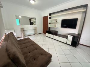 uma sala de estar com um sofá e uma televisão de ecrã plano em Pousada Nonna Mimma em Florianópolis