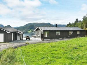 a black house with a lake in the background at 8 person holiday home in Sundlandet in Snildal