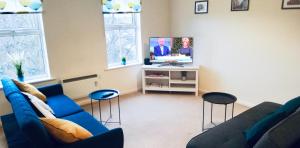 a living room with a blue couch and a tv at Comfortable Apartment in Sheffield with Parking in Neepsend