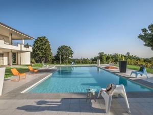 塔武利亞的住宿－Belvilla by OYO Il Panorama Trenta，房屋前设有带椅子和桌子的游泳池