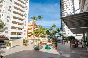 un patio con palmeras, sillas y edificios en Hotel Ave Inn, en Mazatlán