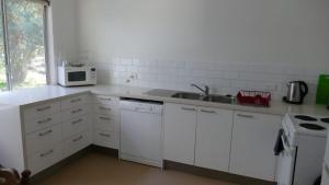 a white kitchen with a sink and a microwave at The Abbey Raymond Island in Raymond Island