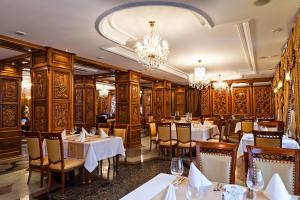 a restaurant with tables and chairs and chandeliers at Richmond Hotel in Yekaterinburg