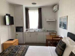 um quarto de hotel com uma cama e uma mesa e uma cozinha em Alpers Lodge & Conference Centre em Auckland