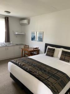 a bedroom with a large bed and a table at Alpers Lodge & Conference Centre in Auckland