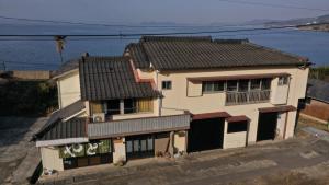 una casa bianca con un tetto nero accanto all'acqua di Saitosyukuba a Sonogi