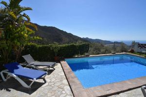 a swimming pool with two lounge chairs and a blue poolvisor at Frigiliana 015 in Frigiliana