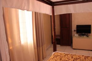 a bedroom with a canopy bed and a television at Moffat Court Boutique Hotel in Mombasa